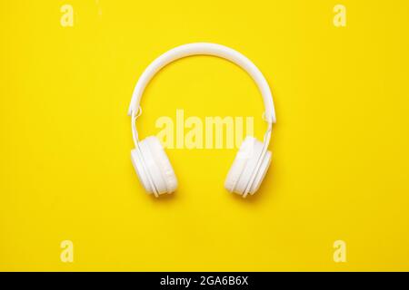 Casque sans fil blanc sur fond jaune. Vue de dessus. Pose à plat. Technologie accessoire taille basse Banque D'Images