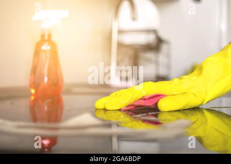 Nettoyage à l'aide d'un détergent en aérosol, de gants en caoutchouc et d'un chiffon à vaisselle sur la surface de travail et le fond de la cuisine Banque D'Images