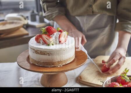 Les mains coupant des fraises avec un couteau sur la planche à découper Banque D'Images