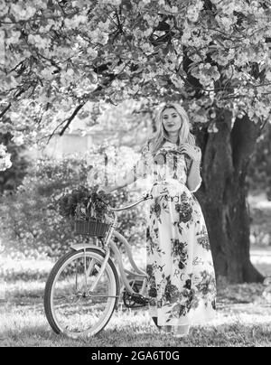 Promenade romantique en vélo. Vacances de printemps. Concept du tourisme. Transport et voyages. Saison Sakura. Femme avec bouquet de tulipes. Fleurs d'arbre Sakura. Fille Banque D'Images