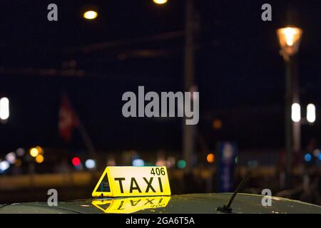 Petit foyer du signe jaune de taxi sur le dessus de la voiture à la nuit avec des lumières floues dans l'arrière-plan Banque D'Images