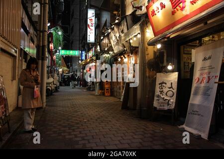 Japon. 24 octobre 2017. Une femme fait une pause près des panneaux de néon lumineux tout en marchant dans le quartier Omoide Yokocho (Memory Lane) de Shinjuku, Tokyo, Japon la nuit, un quartier connu pour sa vie nocturne et sa scène de bar, 24 octobre 2017. (Photo par Smith Collection/Gado/Sipa USA) crédit: SIPA USA/Alay Live News Banque D'Images