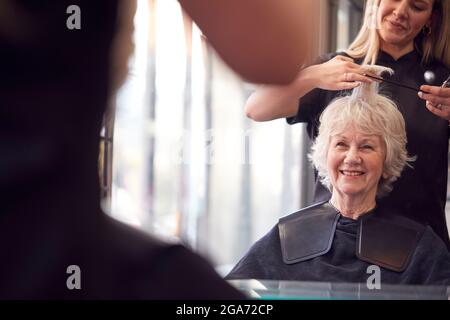 Femme sénior ayant des cheveux coupés par la styliste féminine dans le salon de coiffure Banque D'Images