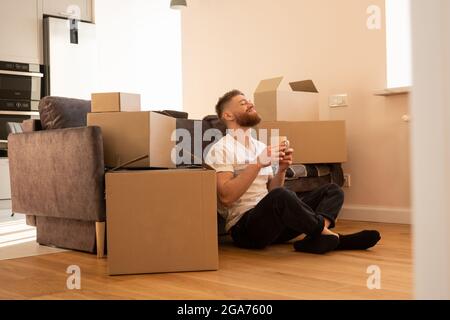 Homme au repos assis sur le sol et buvant du thé Banque D'Images