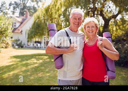 Portrait d'un couple Senior à la maison dans le jardin portant des vêtements de fitness prêt pour une session de yoga en plein air Banque D'Images
