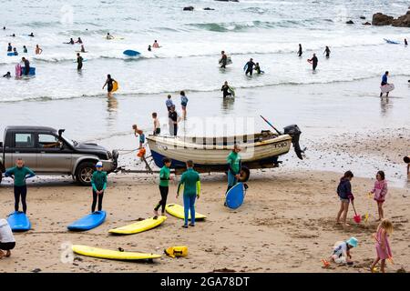 Trevaunance Cove,Cornwall,29 juillet 2021,UNE voiture pousse un canot en bois sur la plage tandis que Surfers a profité des vagues de Trevaunance Cove devant Storm Evert à St Agnes, Cornwall. La quatrième tempête d'été nommée est due à apporter des vents forts et de fortes pluies insaisonnières de nuit. Crédit : Keith Larby/Alay Live News Banque D'Images