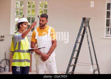 Femme Surveyor avec presse-papiers Réunion avec Décorateur travaillant à l'intérieur de la propriété Banque D'Images