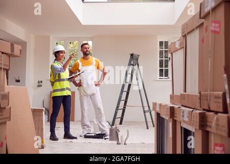 Femme Surveyor avec presse-papiers Réunion avec Décorateur travaillant à l'intérieur de la propriété Banque D'Images