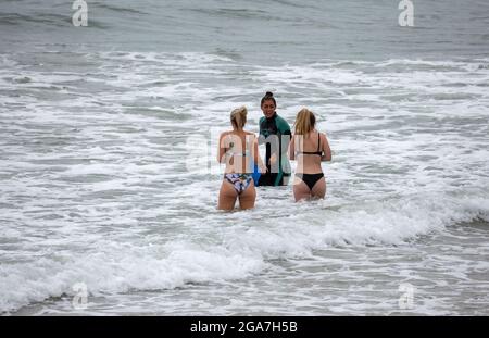 Trevarunance Cove,Cornwall,29 juillet 2021,trois dames nageaient dans la mer à Trevarunance Cove devant Storm Evert à St Agnes,Cornwall. La quatrième tempête d'été nommée est due à apporter des vents forts et de fortes pluies insaisonnières de nuit. Pendant que les surfeurs étaient dans l'eau les vacanciers aussi assis sur les grands rochers au sommet de la plage comme la marée s'est sorti.Credit: Keith Larby/Alay Live New Banque D'Images