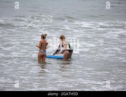 Trevarunance Cove,Cornwall,29 juillet 2021,trois dames nageaient dans la mer à Trevarunance Cove devant Storm Evert à St Agnes,Cornwall. La quatrième tempête d'été nommée est due à apporter des vents forts et de fortes pluies insaisonnières de nuit. Pendant que les surfeurs étaient dans l'eau les vacanciers aussi assis sur les grands rochers au sommet de la plage comme la marée s'est sorti.Credit: Keith Larby/Alay Live New Banque D'Images