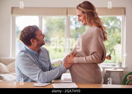 Couple avec l'homme touchant l'estomac de Womans enceinte comme elle se tient à côté de lui Banque D'Images