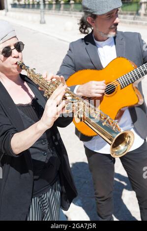 Musiciens de jazz vêtus de style rétro jouant dans la rue. Une femme brune avec chapeau et lunettes de soleil jouant clarinette au premier plan et dans la ba Banque D'Images