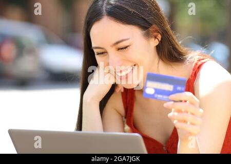 Femme asiatique achetant en ligne avec carte de crédit et ordinateur portable dans la rue Banque D'Images