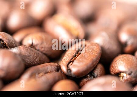Photo macro des grains de café frits sur la table. Fond de grains de café fraîchement torréfiés Banque D'Images