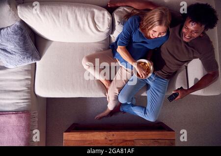 Vue en hauteur d'un couple d'âge mûr reposant sur un canapé à la maison regardant la télévision ensemble Banque D'Images