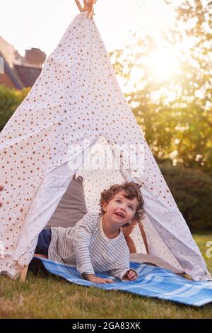 Jeune garçon ayant du plaisir à l'intérieur de la tente ou Tepee perché dans le jardin Banque D'Images