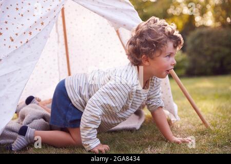 Jeune garçon ayant du plaisir à l'intérieur de la tente ou Tepee perché dans le jardin Banque D'Images