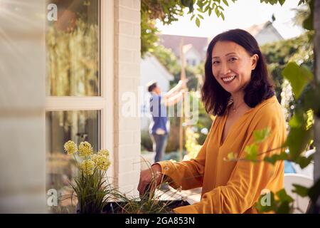 Portrait d'une femme asiatique mûre plantant des plantes dans un jardinier en bois à la maison Banque D'Images