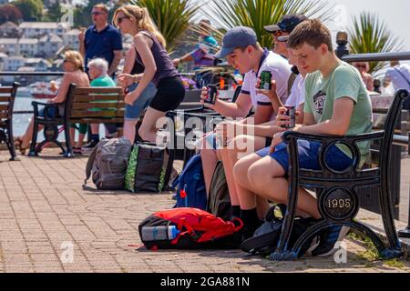Les visiteurs de Fowey s'assoient et se détendent sur le front de mer - Fowey, sud de Cornwall, Royaume-Uni. Banque D'Images