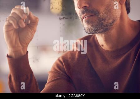 Gros plan d'un homme d'affaires ou d'un mathématicien calcul graphique sur écran verre dans Office Banque D'Images