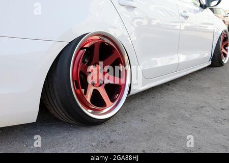 Voiture blanche réglée avec suspension extrêmement basse et roues rouges. Mise au point sélective. Banque D'Images