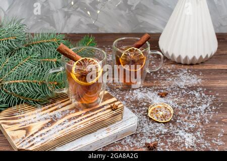 Carte de Noël du nouvel an. Deux tasses de thé en verre avec des bâtonnets de citron et de cannelle sur le fond des guirlandes de Noël et des branches d'un arbre de Noël Banque D'Images
