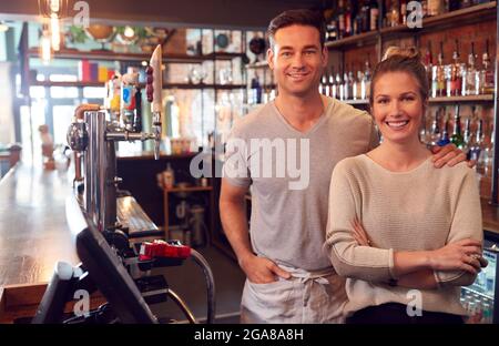 Portrait d'un couple souriant propriétaire d'un bar debout derrière le comptoir Banque D'Images