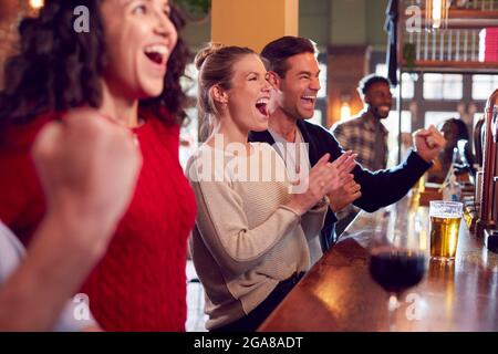 Groupe de clients enthousiastes au Sports Bar regardant un événement sportif à la télévision Banque D'Images