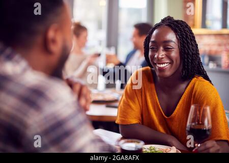 Jeune couple souriant le jour appréciant la pizza au restaurant ensemble Banque D'Images