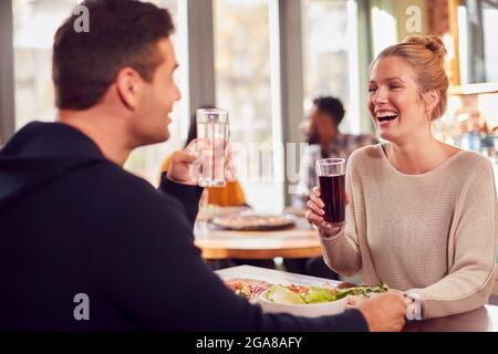 Couple souriant le jour appréciant la pizza au restaurant ensemble Banque D'Images