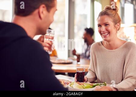 Couple souriant le jour appréciant la pizza au restaurant ensemble Banque D'Images