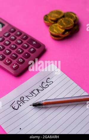 Quelques pièces de monnaie dorées avec une liste de gains sur une feuille de papier, stylo noir et calculatrice rose sur une surface rose Banque D'Images