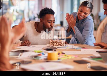 Collègues célébrant l'anniversaire de l'homme d'affaires lors de la réunion autour de la table dans un bureau à plan ouvert moderne Banque D'Images