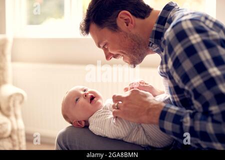 Le Père aimant jouant au jeu avec bébé fils couché sur le circuit à la maison ensemble Banque D'Images