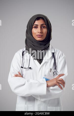 Studio Portrait of Serious Young Doctor avec foulard portant un manteau blanc sur fond Uni Banque D'Images