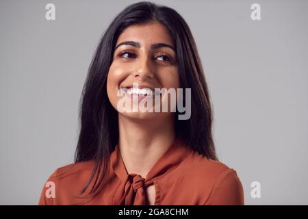 Tête et épaules Studio Portrait de la jeune femme d'affaires souriante sur fond Uni Banque D'Images