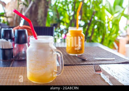 Smoothie froid à base de fruits à la mangue et à l'ananas sur la table dans un café. Repos dans les pays tropicaux, tourisme gastronomique. Banque D'Images