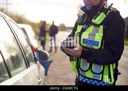 Une femme chargée de la police de la circulation enregistre les détails de l'accident de la route sur un téléphone portable Banque D'Images
