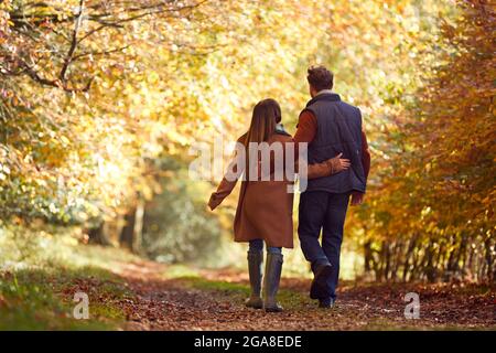 Vue arrière d'un couple d'âge mûr aimant marchant le long de la piste dans la campagne d'automne Banque D'Images