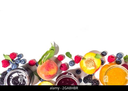 Assortiment de confitures de fruits et de baies de saison d'été en petits pots, concept de conservation maison, marmelades ou des confits avec baies fraîches sur b blanc Banque D'Images