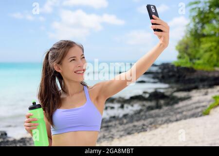 Femme sportive souriante prenant Selfie sur la plage Banque D'Images