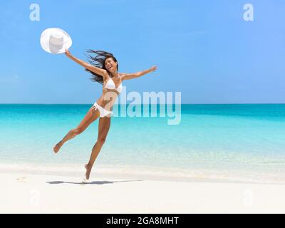 Femme insouciante qui se fait sauter à la plage en été Banque D'Images
