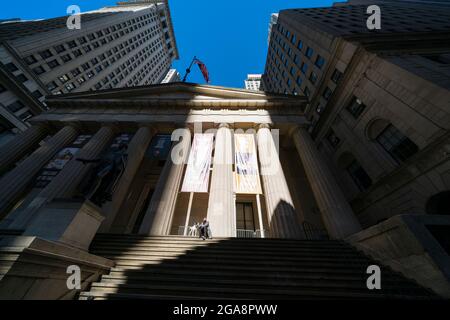 Un homme portant un masque et un chien s'assoit sur l'escalier du bâtiment du Federal Hall de New York. Banque D'Images