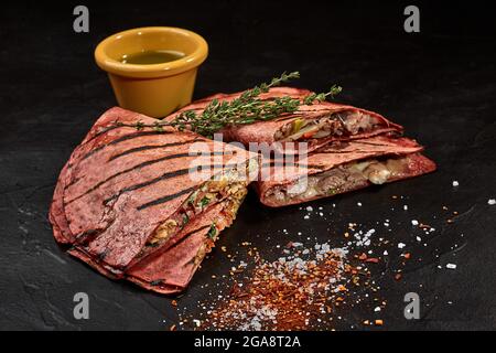 Quesadillas mexicains dans des tortillas de betteraves avec sauce verte épicée Banque D'Images