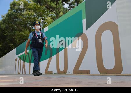 Un policier passe devant un mur de sécurité avec la marque Tokyo 2020 dans le parc marin d'Odaiba le 7 jour des Jeux Olympiques de Tokyo 2020. Banque D'Images