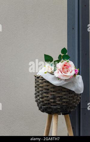 Rose en plastique dans un panier en osier avec un fond gris rugueux Banque D'Images