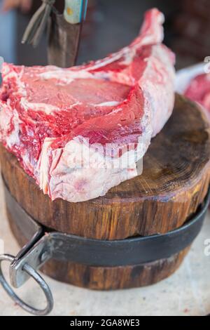 Viande crue sur un pont, un couteau coincé dans la viande. Viande fraîche sur une planche à découper. Gros plan. Banque D'Images