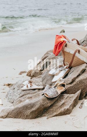 Gros plan de sandales et d'un sac d'été sur la plage pendant une journée ensoleillée Banque D'Images