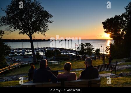 Les gens se détendent sur des bancs dans le parc, regardant un magnifique coucher de soleil, surplombant le port avec des bateaux, à Egg Harbor, comté de Door, Wisconsin, États-Unis Banque D'Images