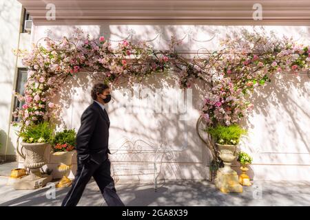 Des fleurs artificielles décorent le mur et des bancs sont placés sur le trottoir sous les fleurs NYC. Banque D'Images